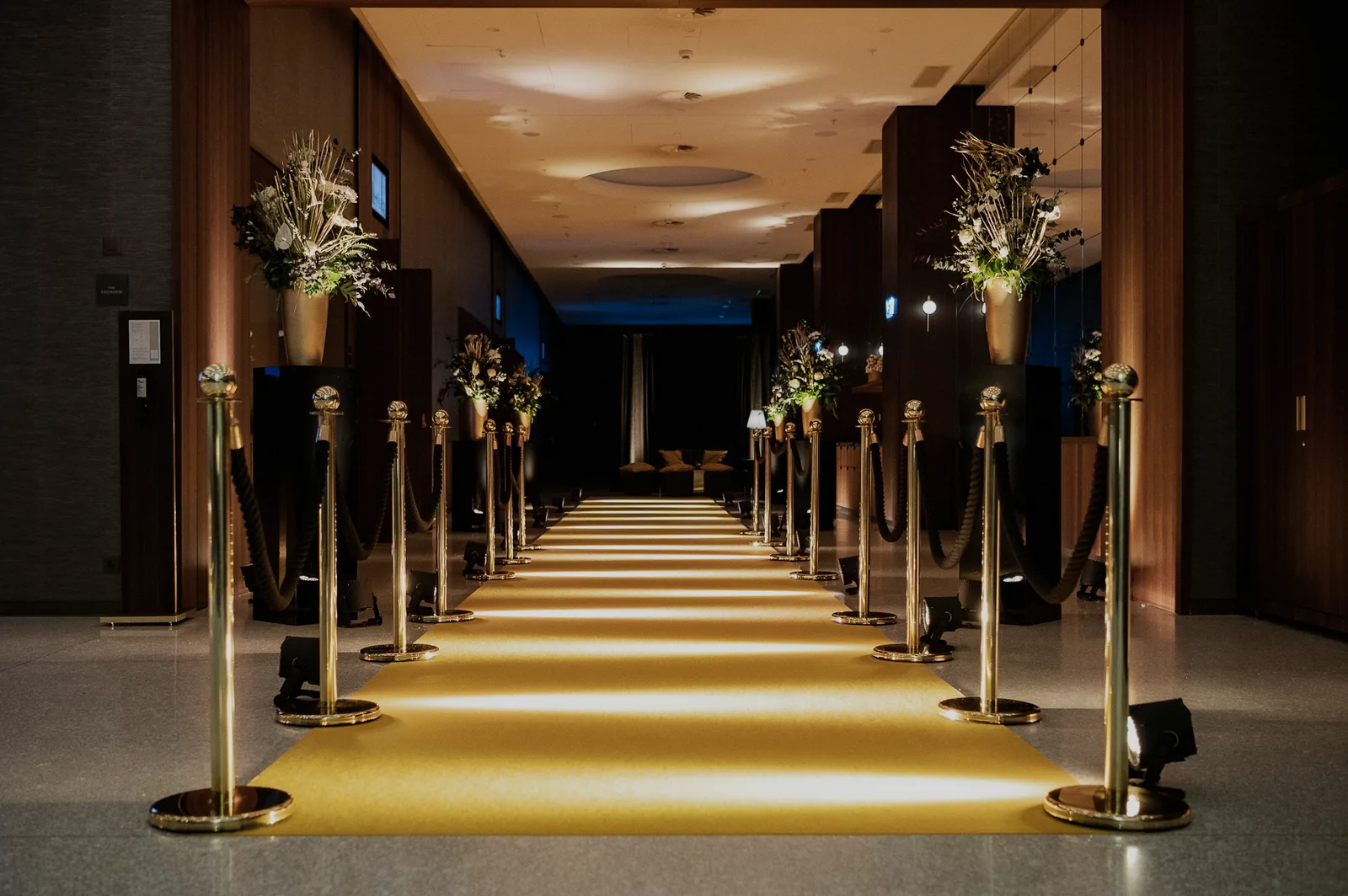 Goldener Teppich mit Absperrständern und Blumenbouquets im Eingangsbereich